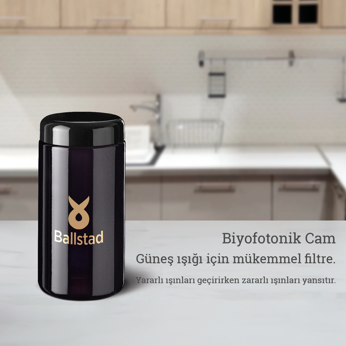 Ballstad logolu koyu renk biyofotonik cam kavanoz mutfak tezgâhında sergileniyor. Yanında “Biyofotonik Cam – Güneş ışığı için mükemmel filtre. Yararlı ışınları geçirirken zararlı ışınları yansıtır.” ifadesi yer almakta.