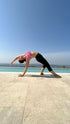 Havuz kenarında, açık havada yoga yapan bir kadın; arka planda mavi gökyüzü ve manzara.