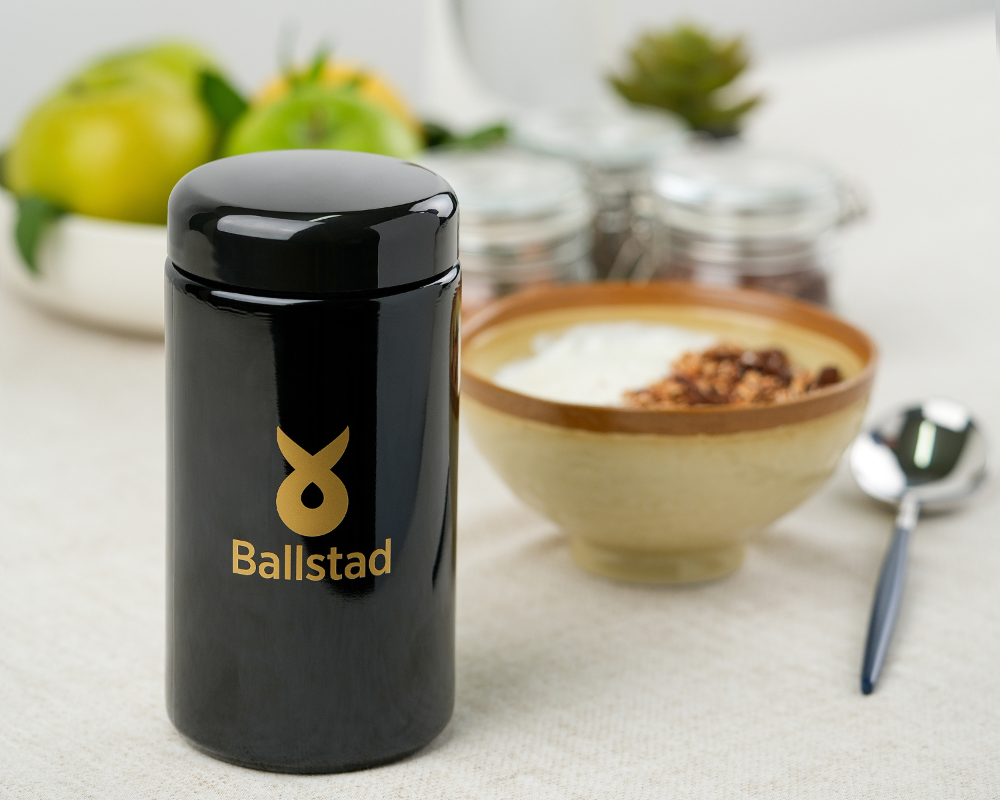 Arkaplanda meyveler ve bir kase yemek ile Ballstad kavanozu