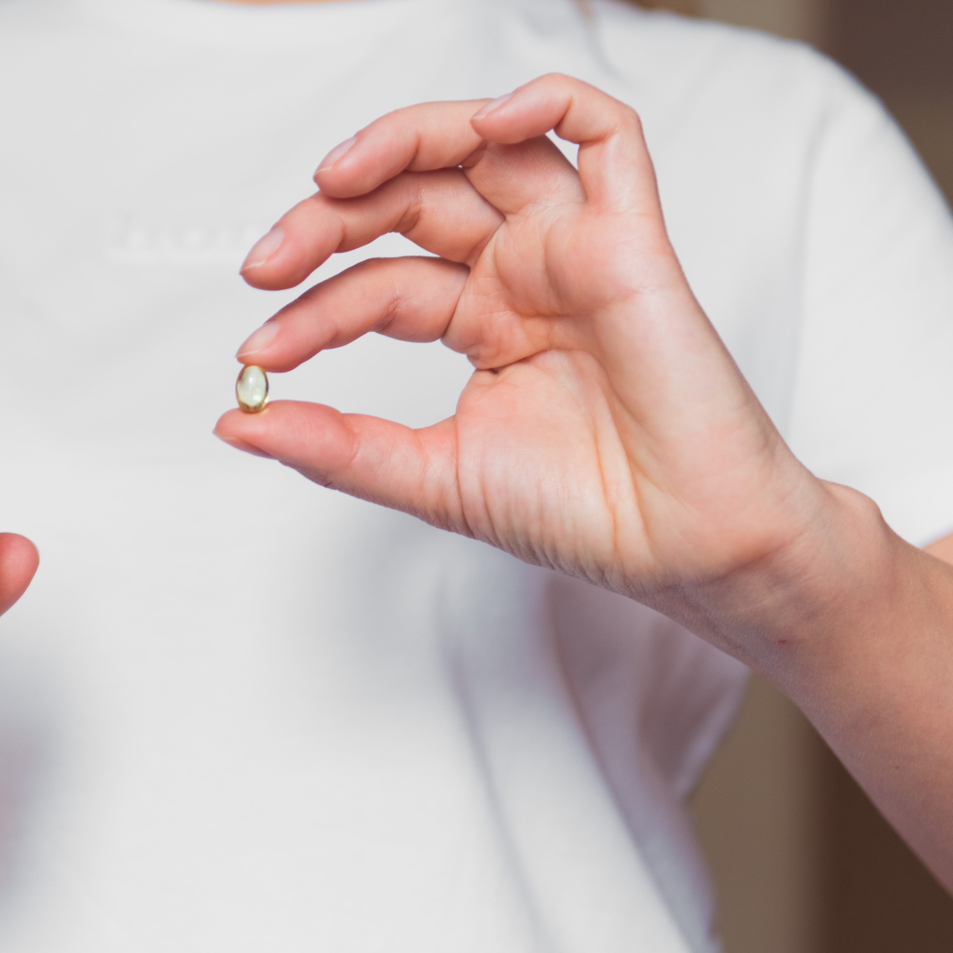 Norveçli yetişkinin  omega3 kapsülü iki parmağı arasındayken