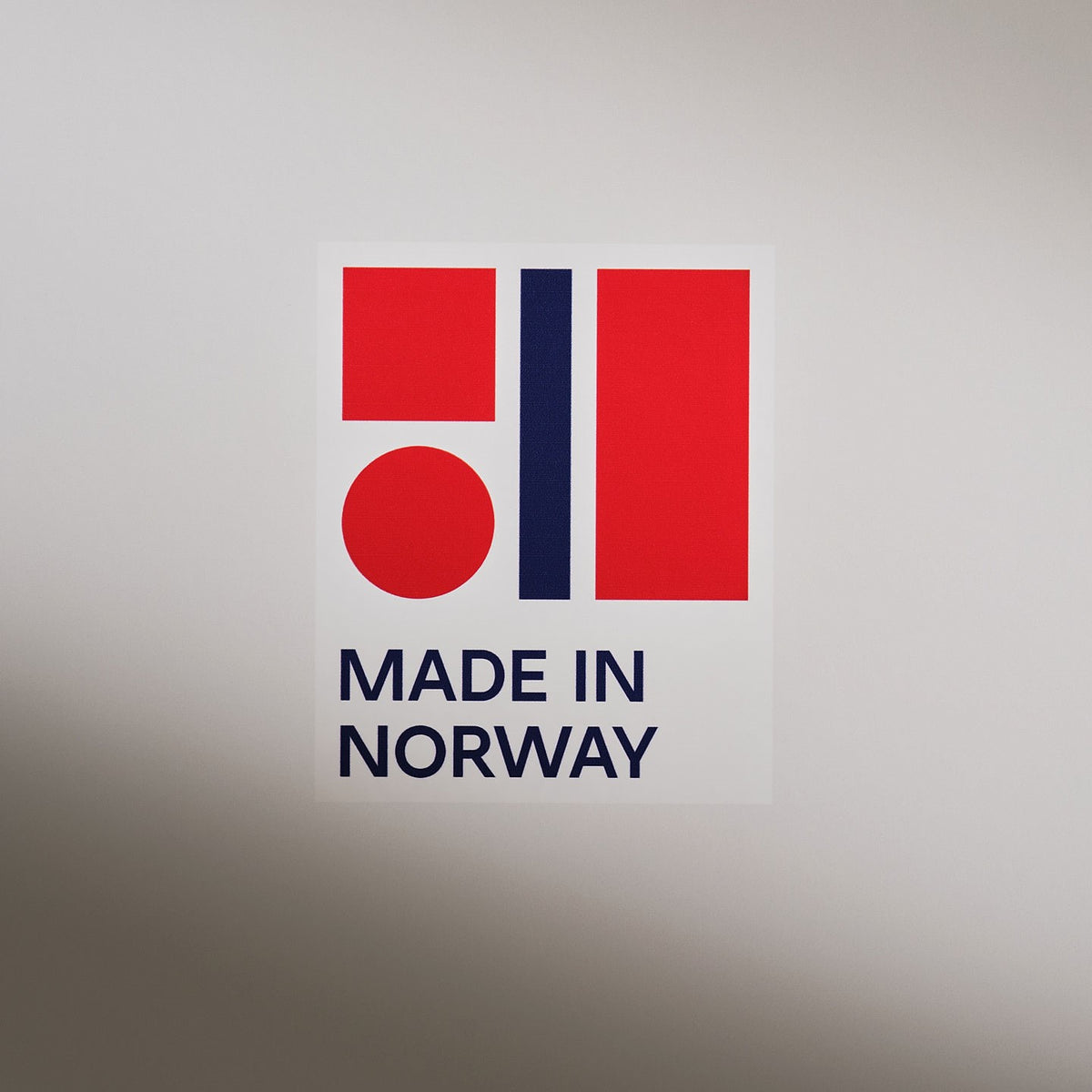 Beyaz zemin üzerinde kırmızı ve lacivert renklerle tasarlanmış 'Made in Norway' (Norveç üretimi) logosu.