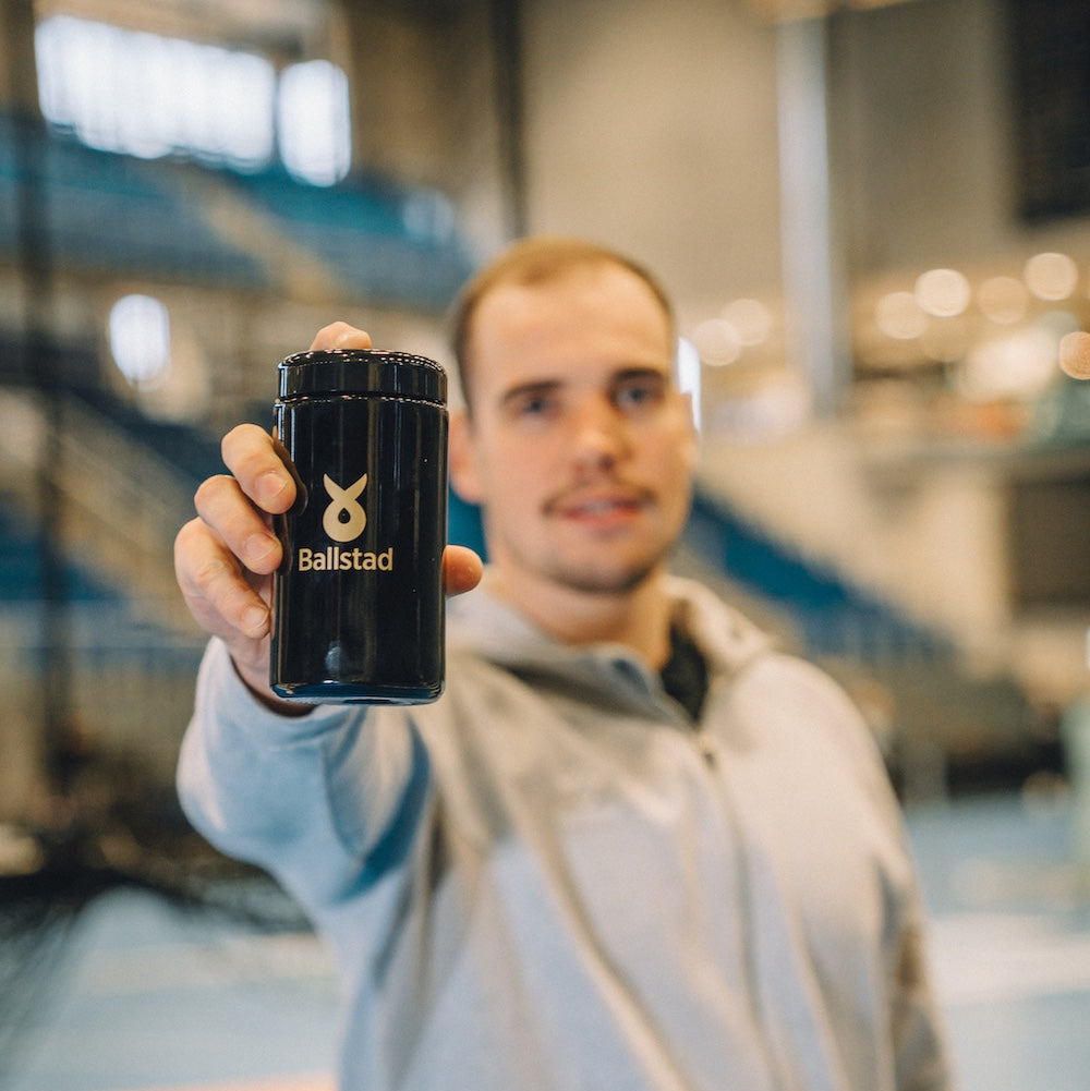 Spor salonunda Ballstad Omega-3 takviyesini tutan genç sporcu — performans, dayanıklılık ve sağlıklı yaşam için destekleyici besin