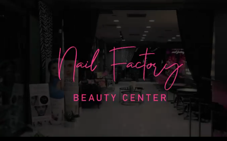 Nail Factory Beauty Center giriş alanı; loş ışıklarla aydınlatılmış modern bir güzellik merkezi ve ön planda pembe yazı tipiyle markanın ismi.